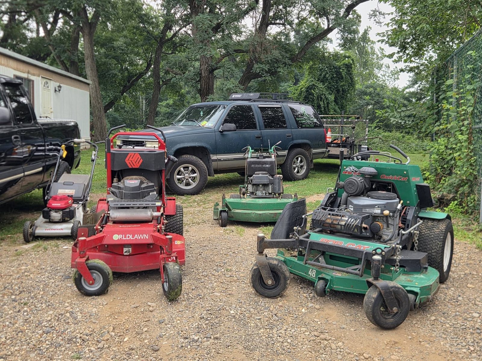 Stand-on and walk-behind commercial mowers parked with the work truck and trailer